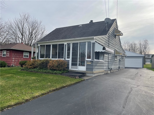 view of front of house featuring a garage, an outbuilding, and a front lawn