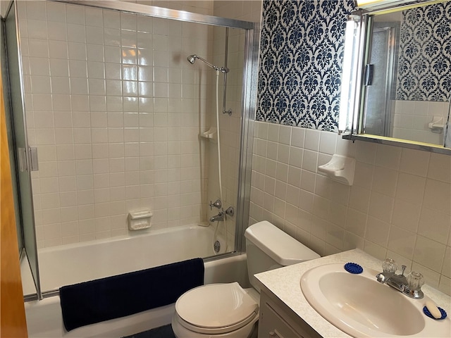 full bathroom with vanity, toilet, tile walls, and tiled shower / bath