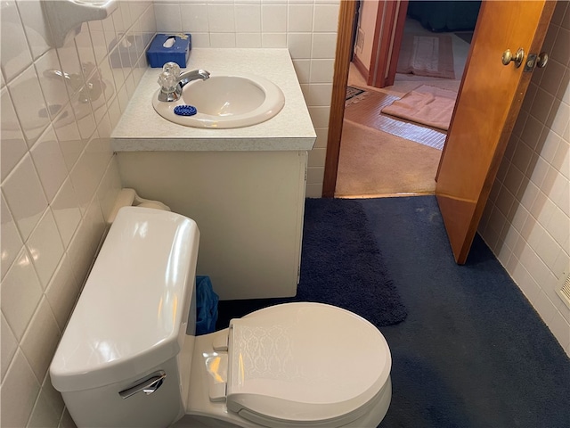 bathroom featuring vanity, tile walls, and toilet