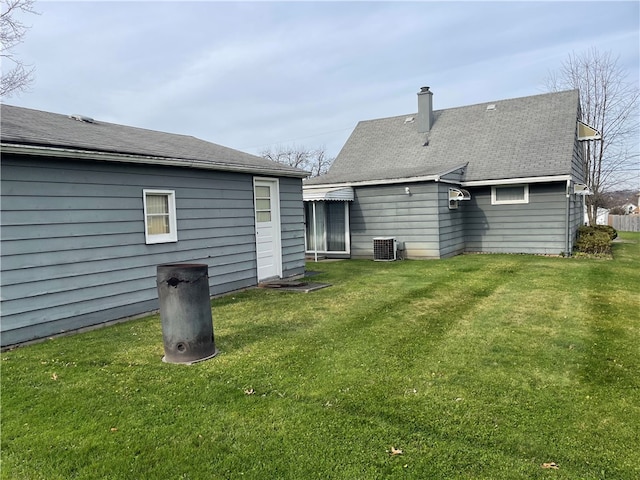 rear view of property featuring a yard and central AC unit