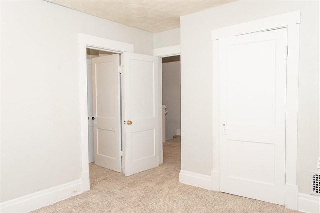 unfurnished bedroom featuring light colored carpet and a closet