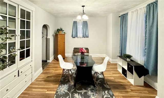 dining space with hardwood / wood-style floors and a notable chandelier