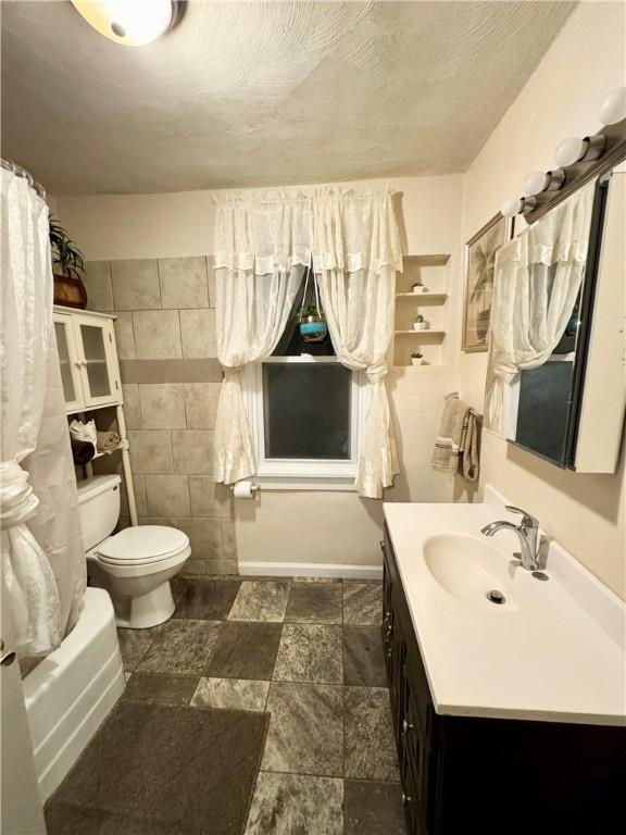 full bathroom featuring vanity, toilet, shower / bathtub combination with curtain, and tile walls