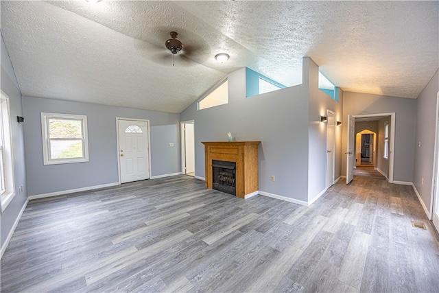 unfurnished living room featuring lofted ceiling, ceiling fan, a textured ceiling, and light wood-type flooring