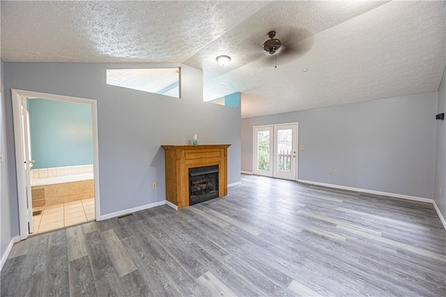 unfurnished living room featuring hardwood / wood-style floors, ceiling fan, lofted ceiling, and a textured ceiling