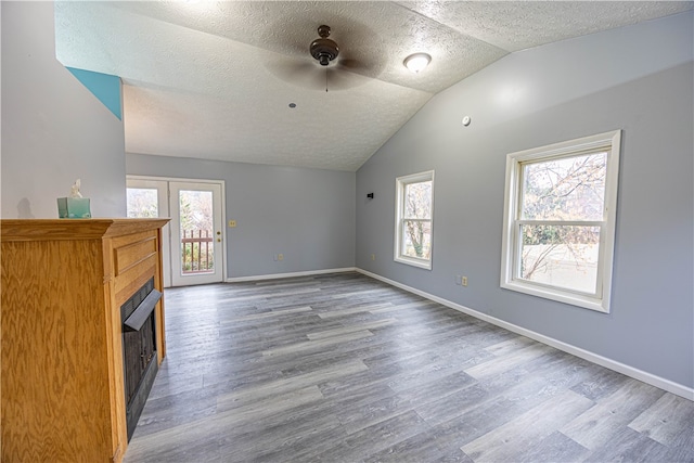 unfurnished living room with a textured ceiling, ceiling fan, lofted ceiling, and hardwood / wood-style flooring