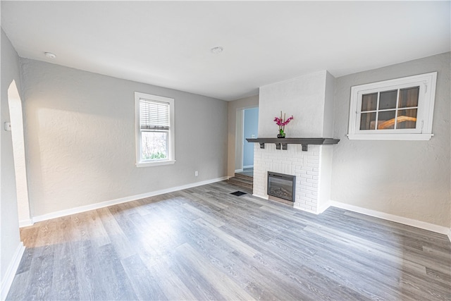 unfurnished living room with hardwood / wood-style floors and a brick fireplace