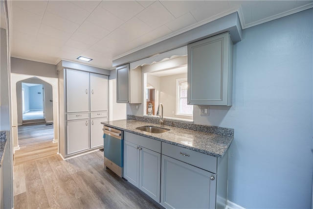 kitchen featuring dark stone counters, sink, stainless steel dishwasher, ornamental molding, and light hardwood / wood-style floors