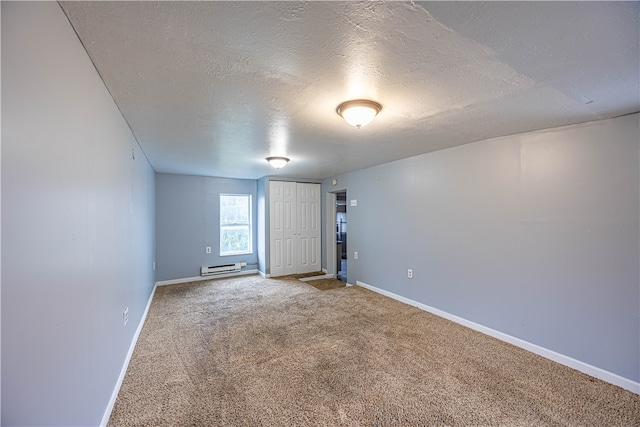 carpeted empty room with baseboard heating and a textured ceiling