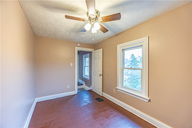 unfurnished room featuring ceiling fan, dark wood-type flooring, and a textured ceiling