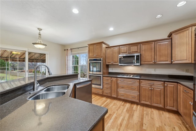 kitchen with light hardwood / wood-style floors, sink, stainless steel appliances, and hanging light fixtures