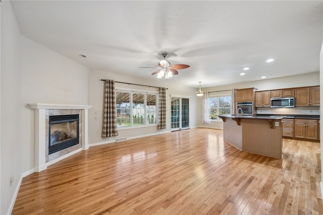 kitchen featuring a kitchen breakfast bar, stainless steel appliances, a kitchen island with sink, decorative light fixtures, and light hardwood / wood-style floors