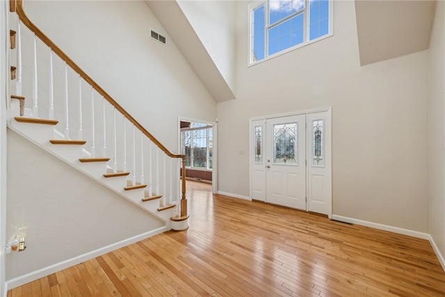 foyer entrance with light hardwood / wood-style flooring and a towering ceiling