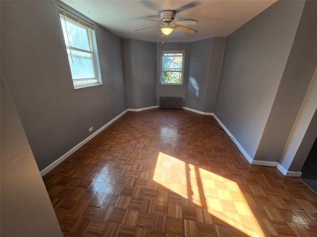 spare room with ceiling fan, dark parquet flooring, and radiator heating unit