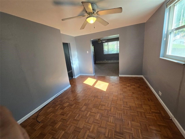 spare room with baseboard heating, ceiling fan, and dark parquet floors