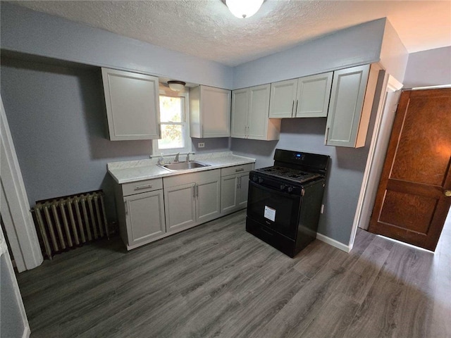 kitchen featuring a textured ceiling, sink, black gas stove, radiator heating unit, and dark hardwood / wood-style floors