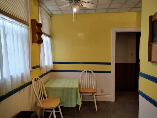 dining area with ceiling fan, a drop ceiling, and carpet floors