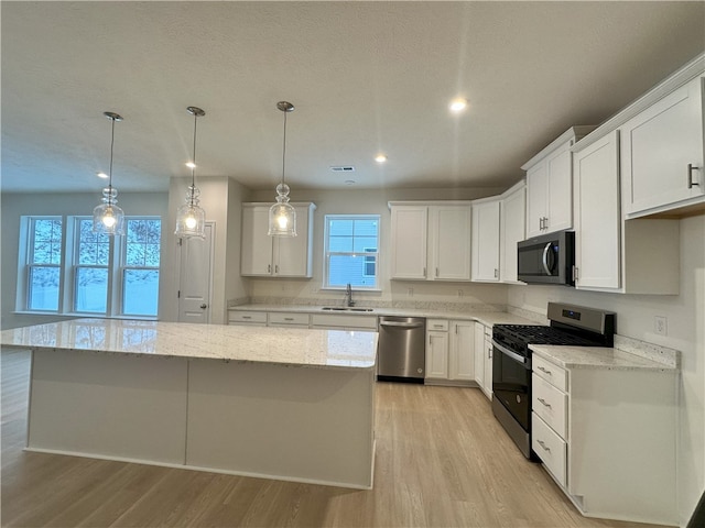 kitchen featuring stainless steel appliances, a kitchen island, sink, and white cabinets