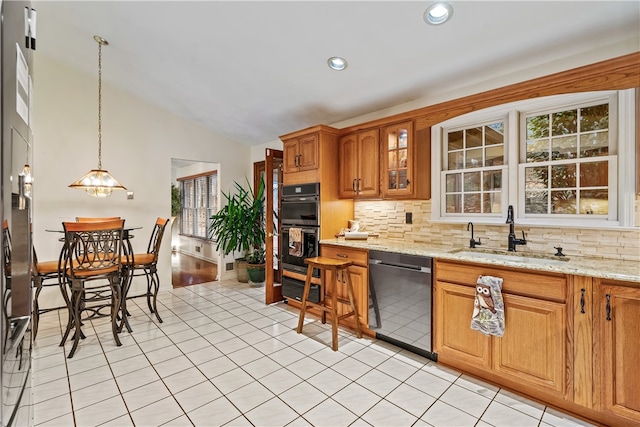 kitchen featuring dishwasher, sink, hanging light fixtures, double oven, and light stone counters