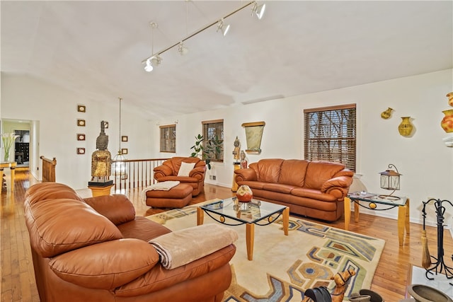 living room featuring light hardwood / wood-style flooring, rail lighting, and lofted ceiling