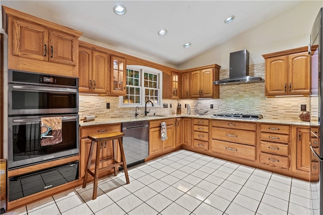 kitchen featuring lofted ceiling, wall chimney exhaust hood, appliances with stainless steel finishes, tasteful backsplash, and light stone counters