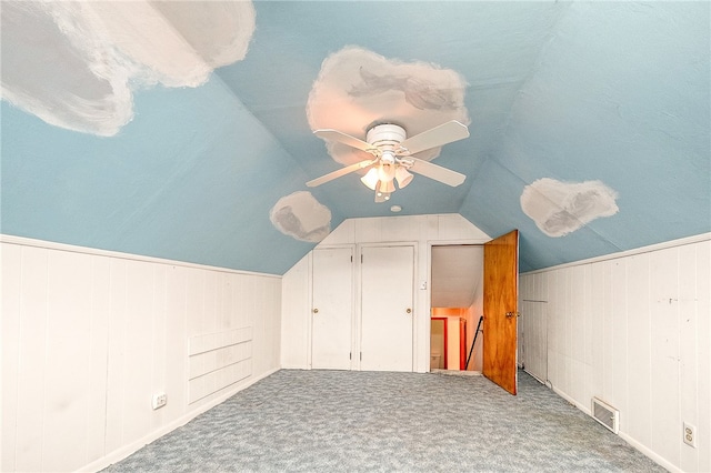 bonus room featuring carpet flooring, wood walls, ceiling fan, and vaulted ceiling