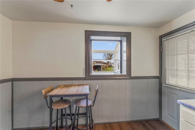 dining room with wooden walls and dark wood-type flooring