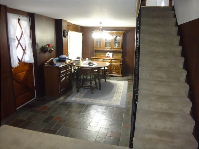 dining area featuring wood walls and a chandelier