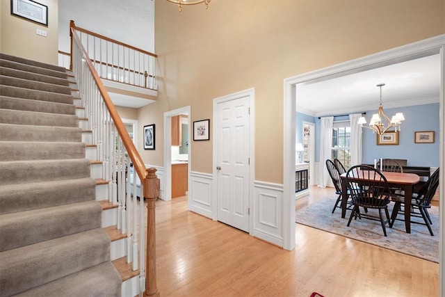 foyer featuring wood-type flooring, crown molding, and a chandelier