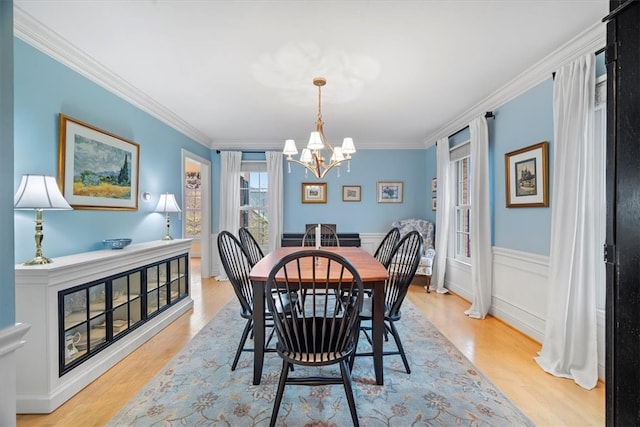 dining area featuring crown molding, light hardwood / wood-style flooring, and a chandelier