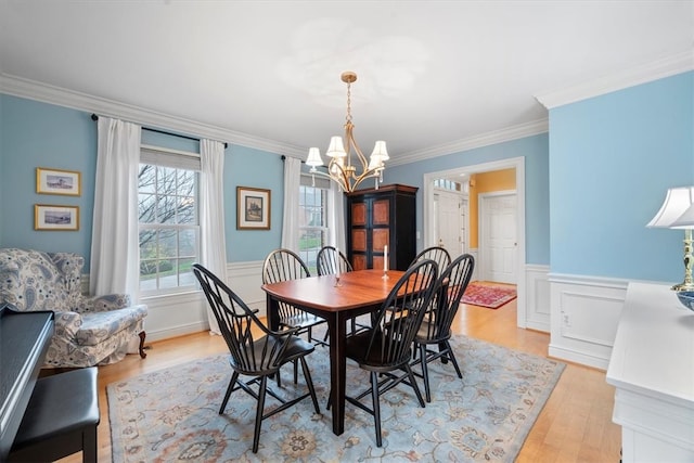 dining space featuring light hardwood / wood-style floors, ornamental molding, and a notable chandelier