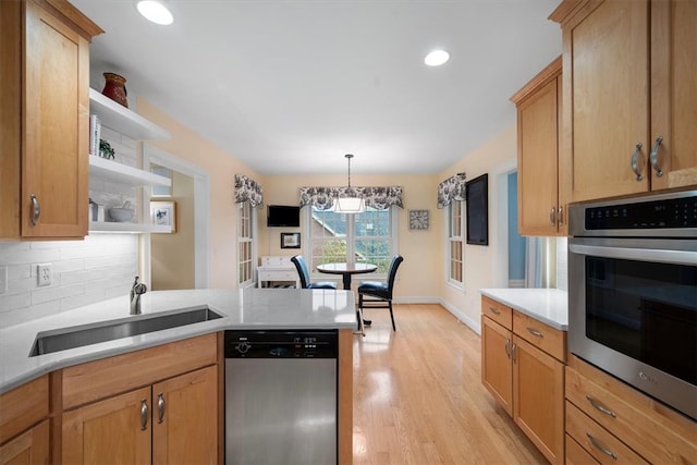 kitchen featuring an inviting chandelier, hanging light fixtures, sink, light hardwood / wood-style flooring, and appliances with stainless steel finishes