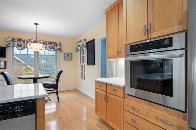 kitchen with pendant lighting, decorative backsplash, light hardwood / wood-style flooring, and stainless steel appliances