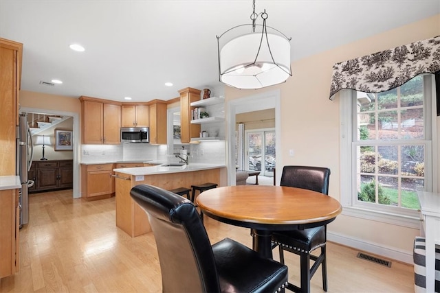 dining room featuring light wood-type flooring, sink, and a wealth of natural light