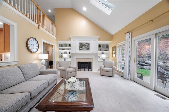 living room featuring carpet, built in shelves, high vaulted ceiling, and a skylight