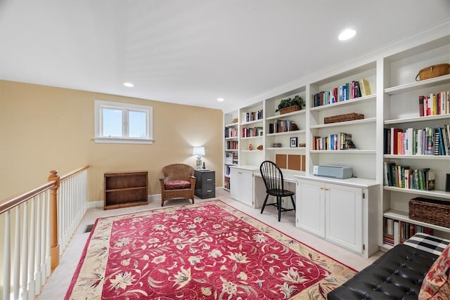 carpeted home office featuring built in shelves and built in desk