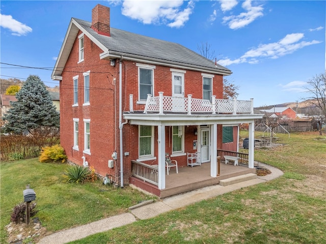 view of front facade with a balcony, covered porch, and a front yard