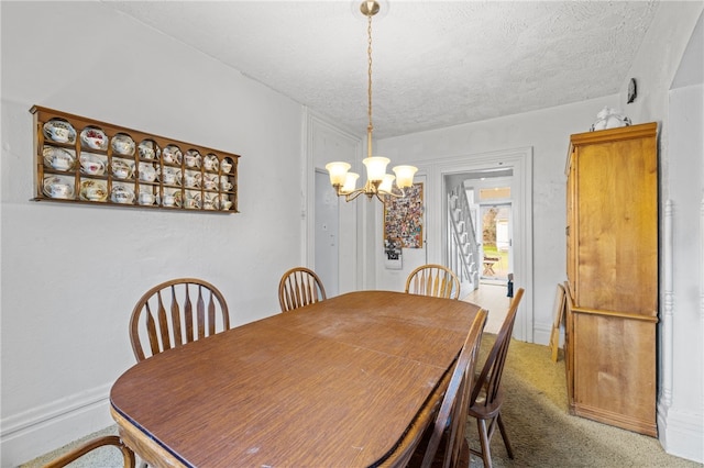 dining space with carpet, a textured ceiling, and a notable chandelier