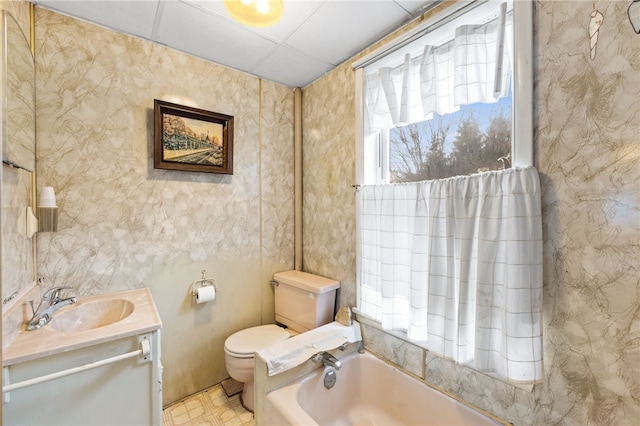 bathroom featuring a paneled ceiling, vanity, a bath, and toilet