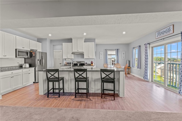 kitchen with plenty of natural light, a kitchen island with sink, stainless steel appliances, and a breakfast bar area