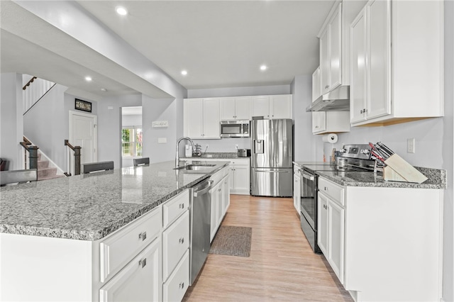 kitchen with white cabinetry, sink, an island with sink, light hardwood / wood-style floors, and appliances with stainless steel finishes