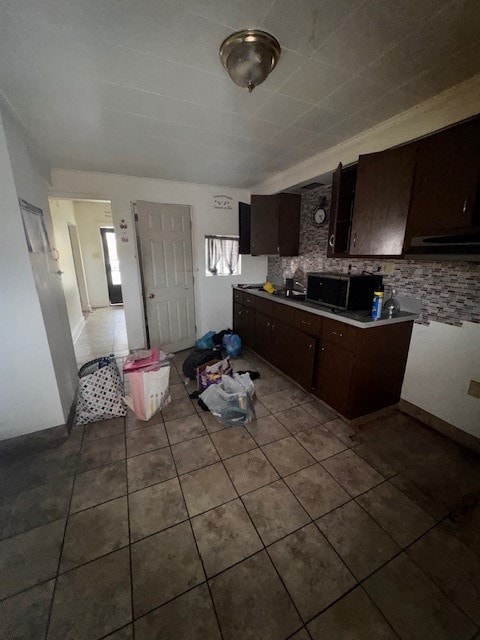 kitchen with tasteful backsplash, dark brown cabinets, and light tile patterned floors