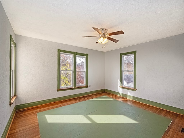 empty room with hardwood / wood-style flooring, ceiling fan, and a textured ceiling