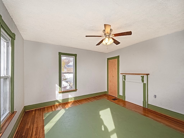 unfurnished room with a wealth of natural light, a textured ceiling, and hardwood / wood-style flooring