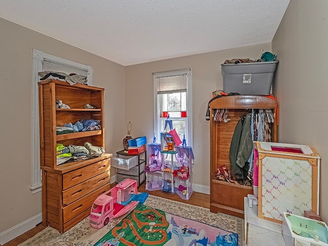 playroom featuring light hardwood / wood-style floors and a textured ceiling