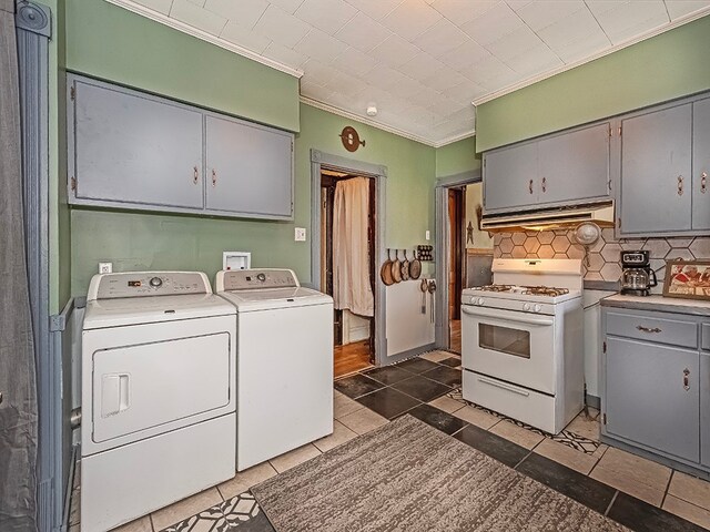 washroom featuring dark tile patterned floors, crown molding, and washing machine and clothes dryer