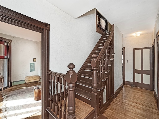 stairs featuring baseboard heating and hardwood / wood-style floors