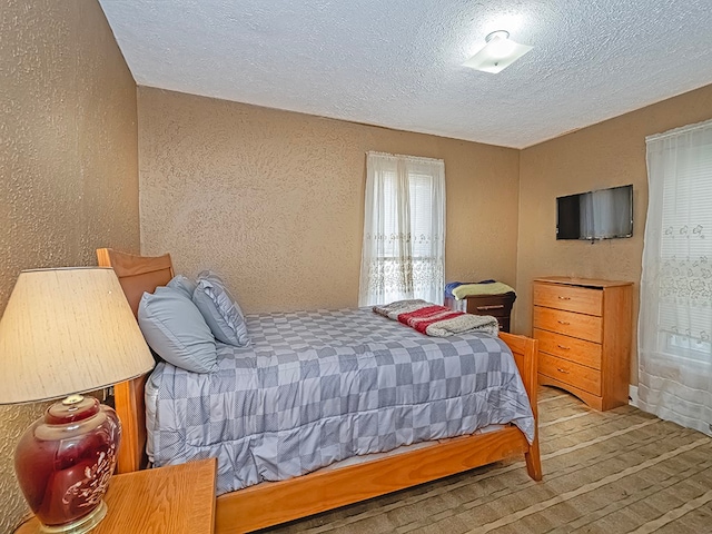 bedroom with light wood-type flooring and a textured ceiling