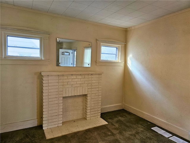 unfurnished living room featuring a brick fireplace, ornamental molding, and dark colored carpet