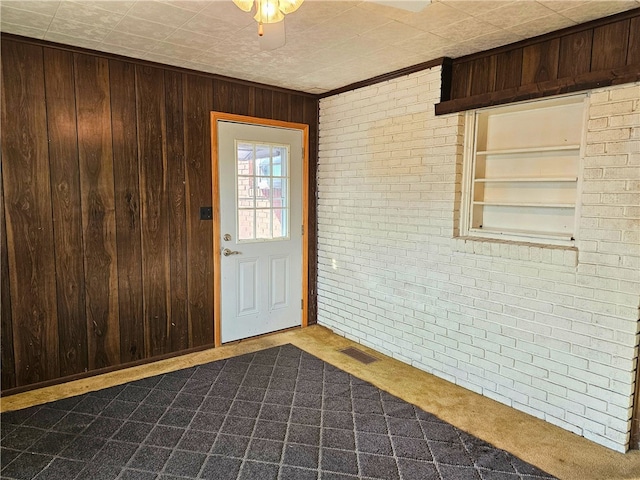 interior space featuring brick wall, crown molding, and wooden walls